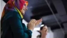 a woman in a brightly coloured headscarf applauding