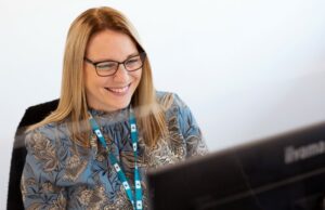 Lady with blonde hair smiling into a computer.